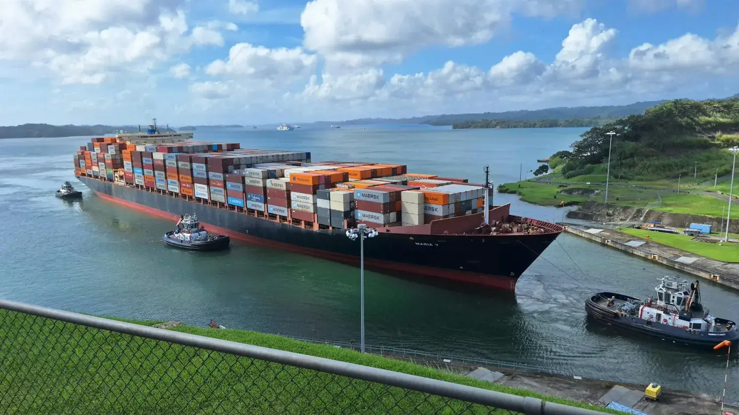 Porte-conteneurs escorté par des remorqueurs sur le canal de Panama